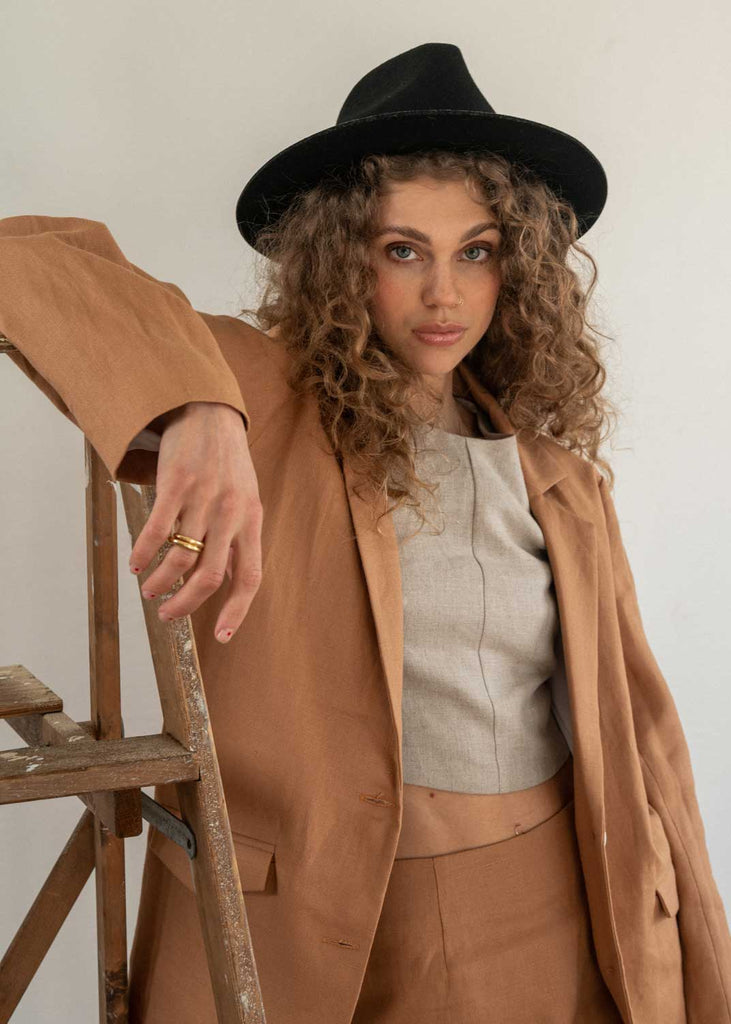 The Sienna Blazer in Camel. Our linen blazer is made locally in Vancouver, Canada. Our model styles it with our matching skirt and Oat Eden Tank for the perfect business casual look.